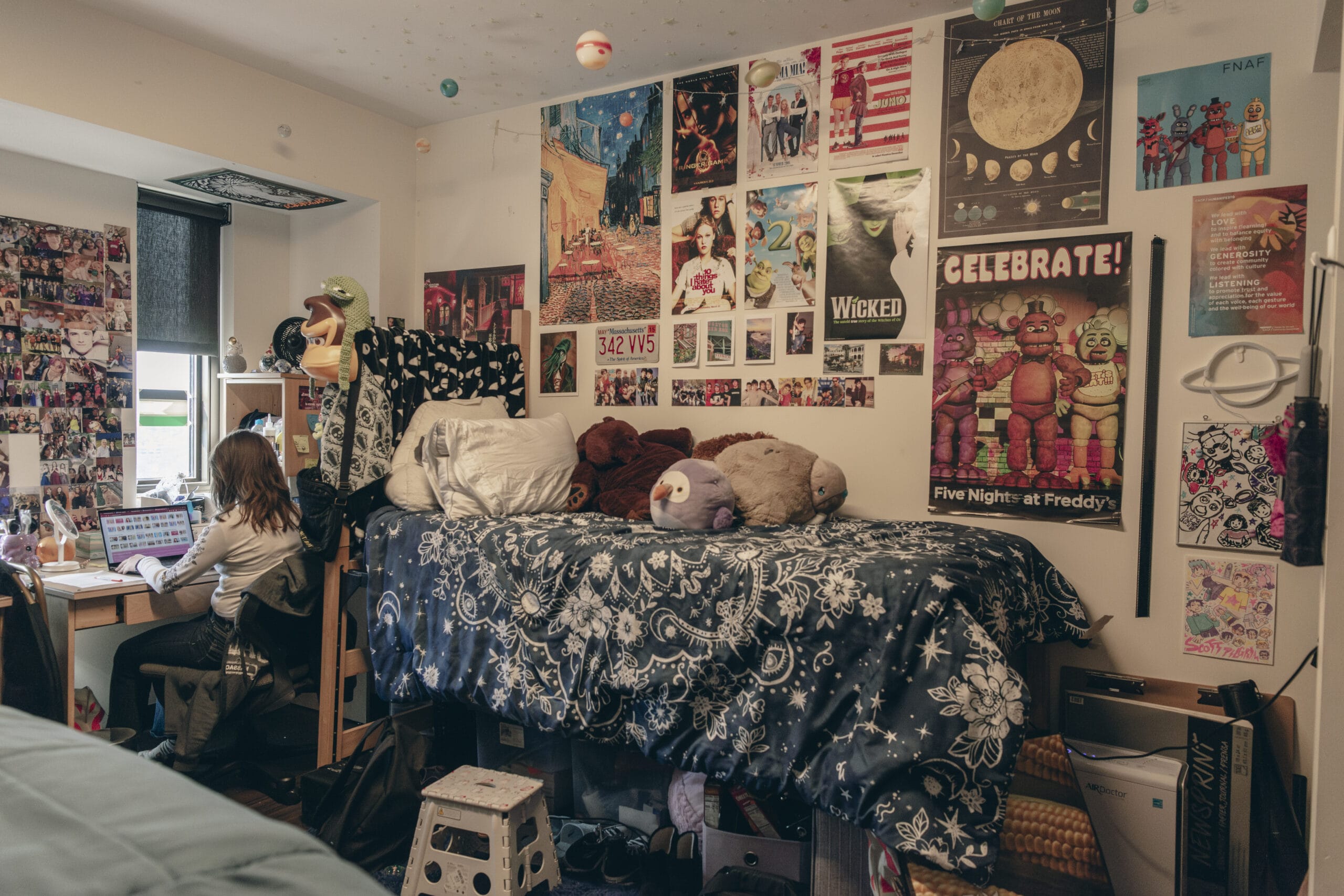 A dorm room with lots of posters on the wall