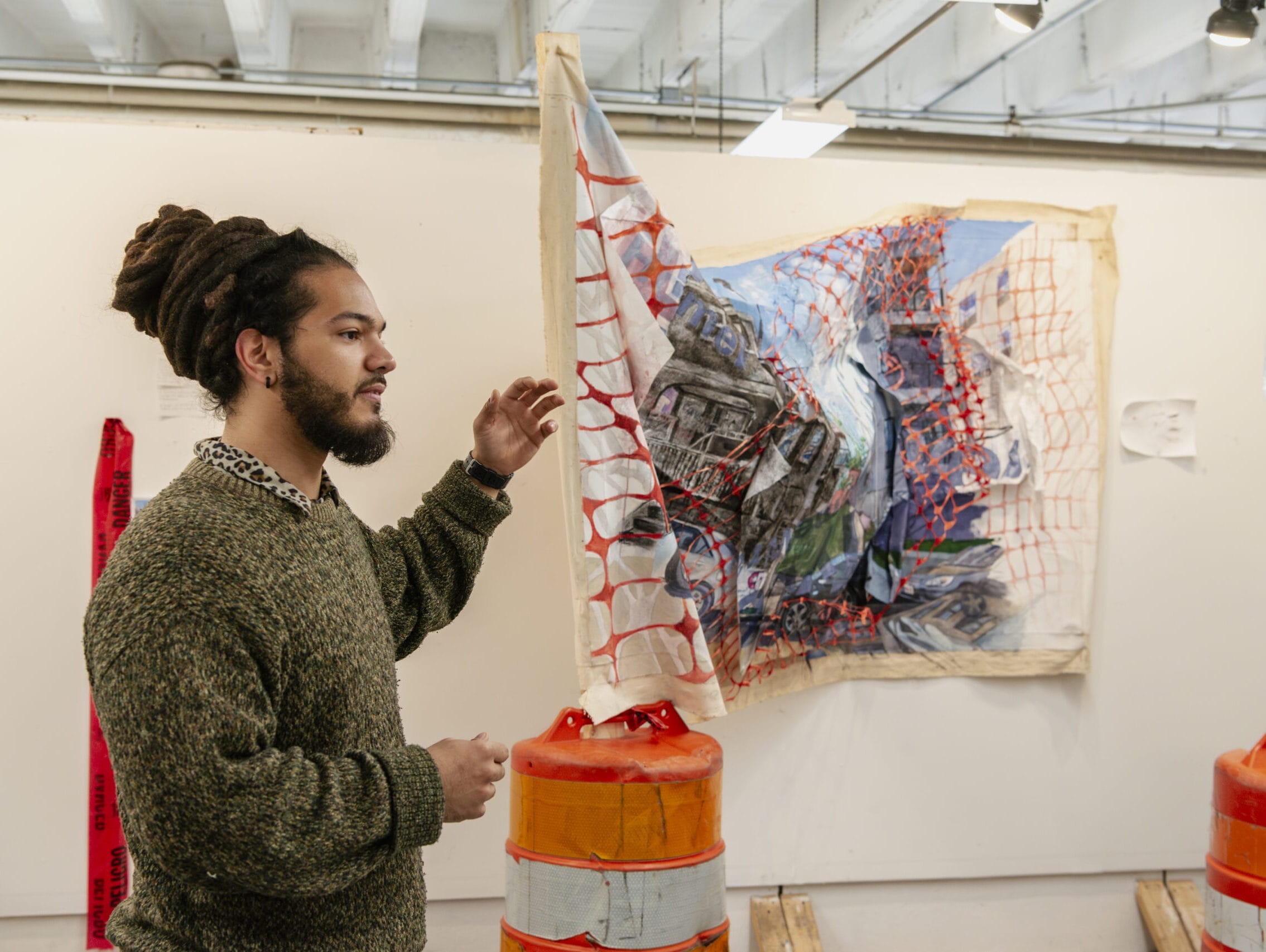 Student standing in his studio pointing to a 3 dimensional artwork