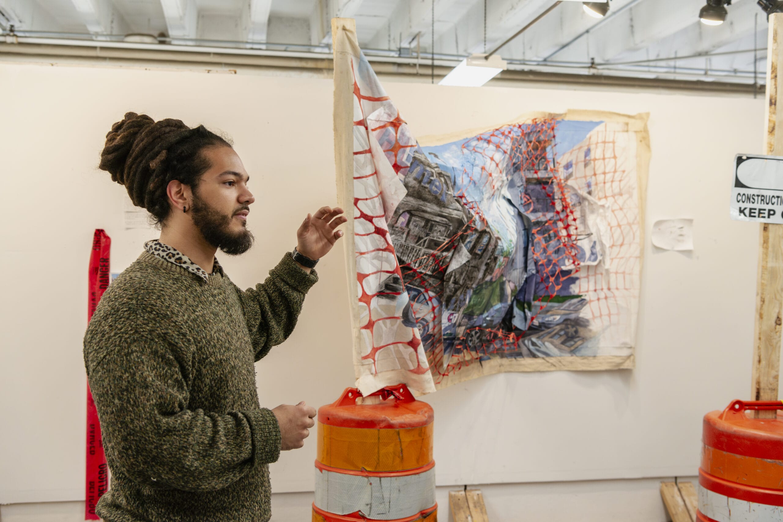 Student standing in his studio pointing to a 3 dimensional artwork