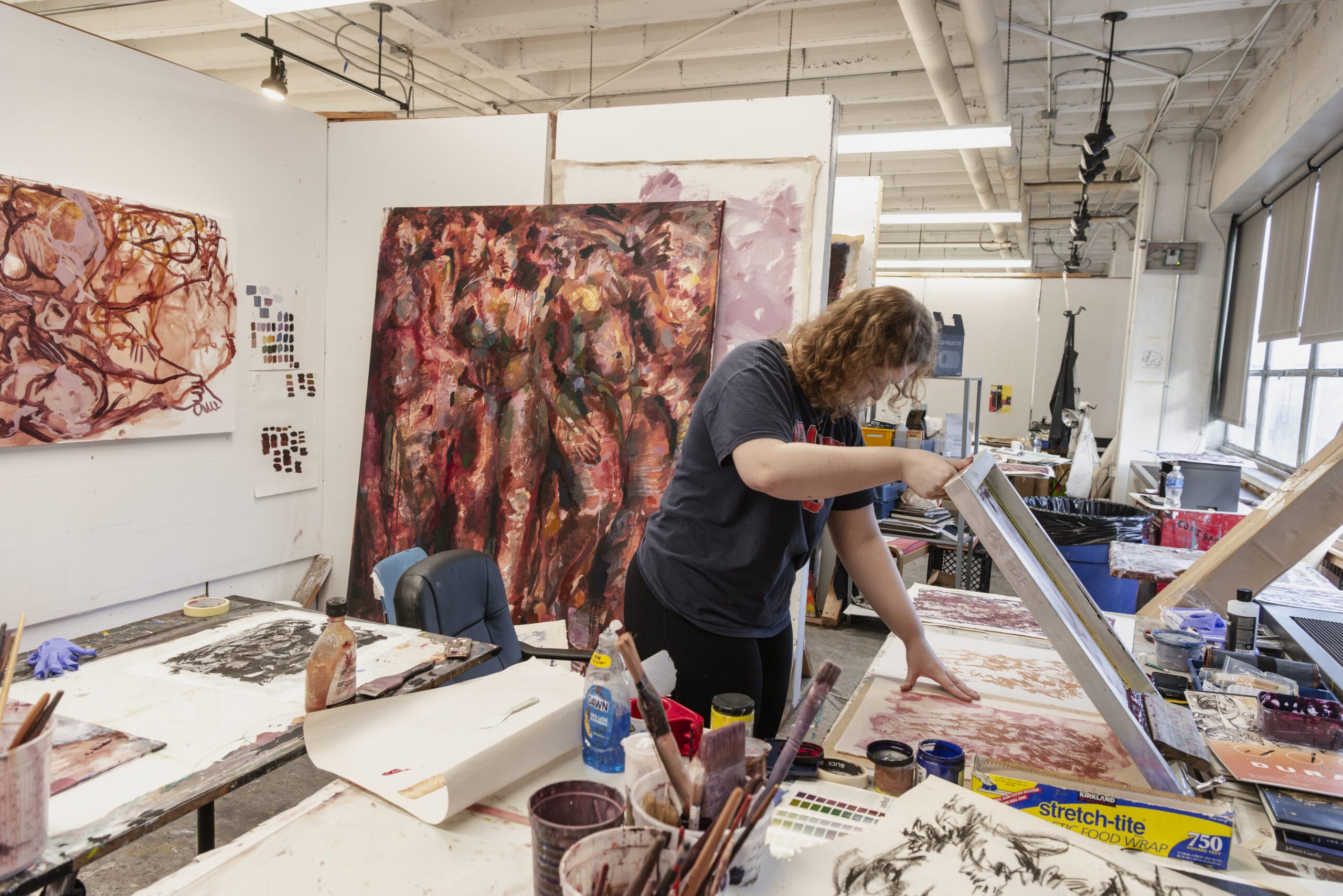 A student lifts a printmaking screen while working in her studio