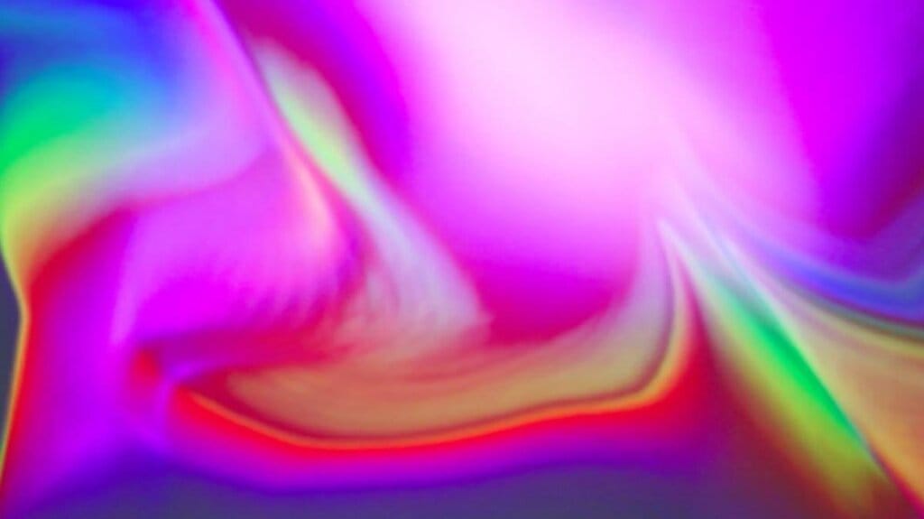 A vibrant abstract image featuring a swirl of vivid colors, including pink, purple, red, and green. The colors blend smoothly, creating a fluid and dynamic appearance reminiscent of a nebula or colorful gradient.