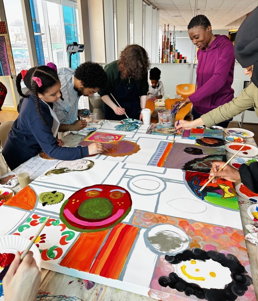 People stand around a table painting