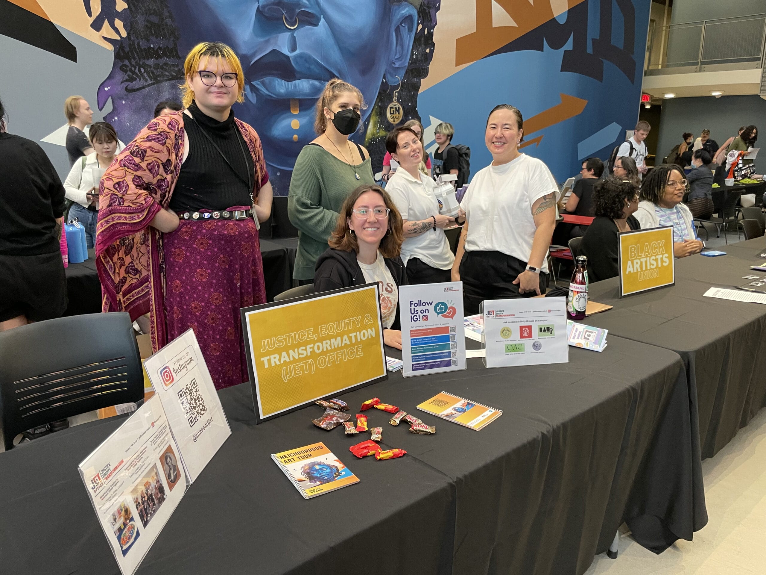 Students stand around the Justice, Equity, and Transformation table at a Student Engagement fair