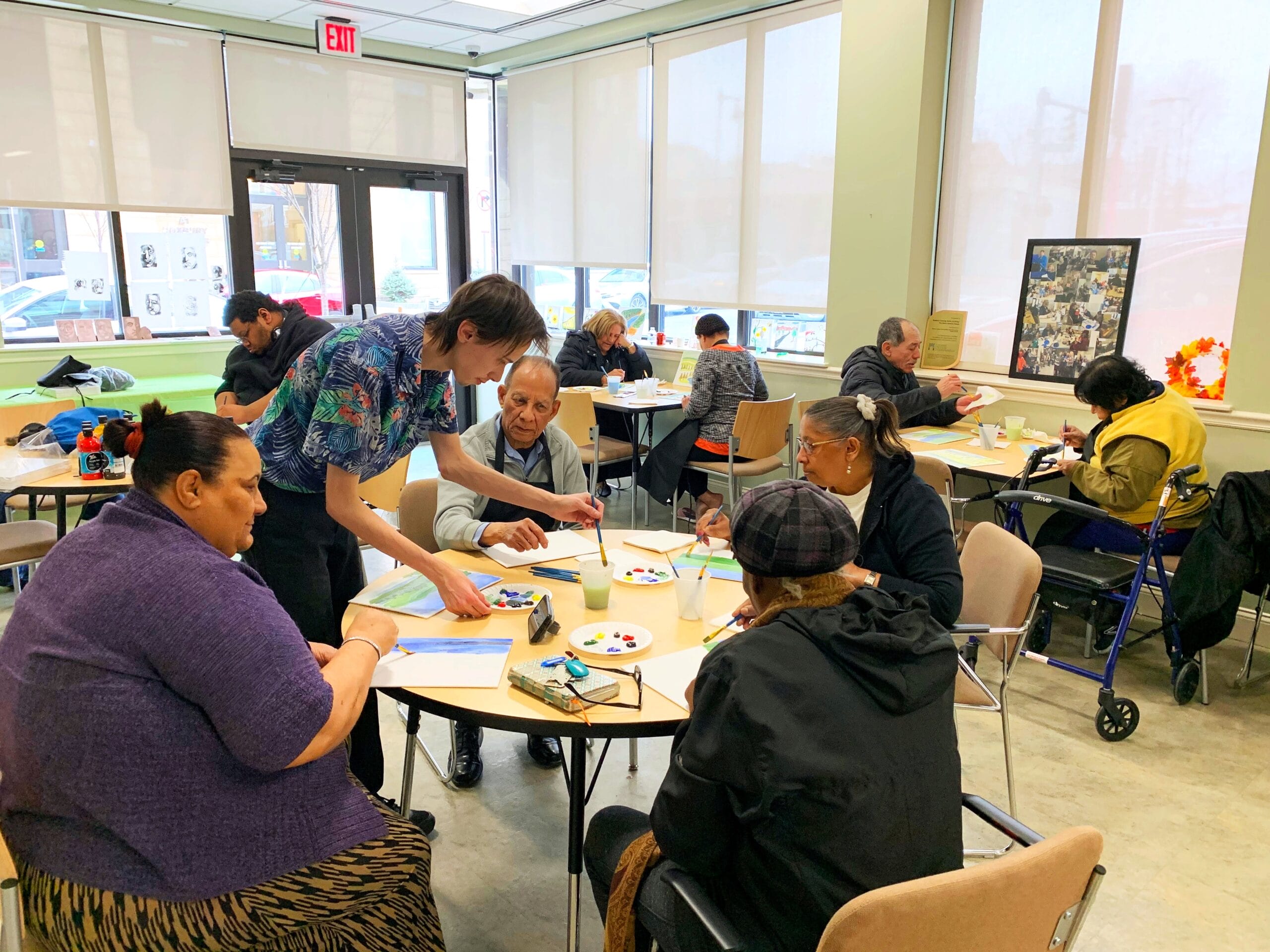 Older community members sit at round tables doing an activity