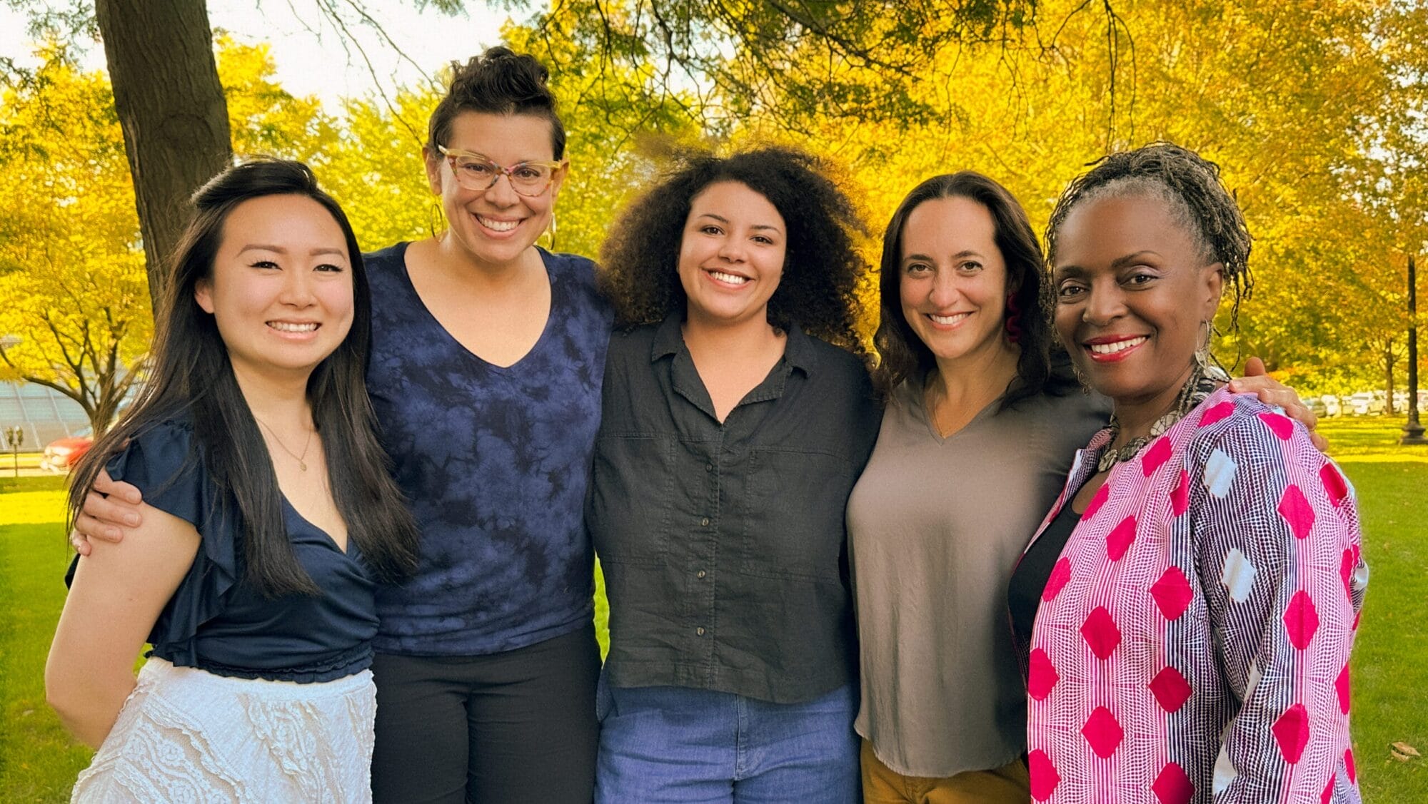 Photo of five women smiling at the camera.