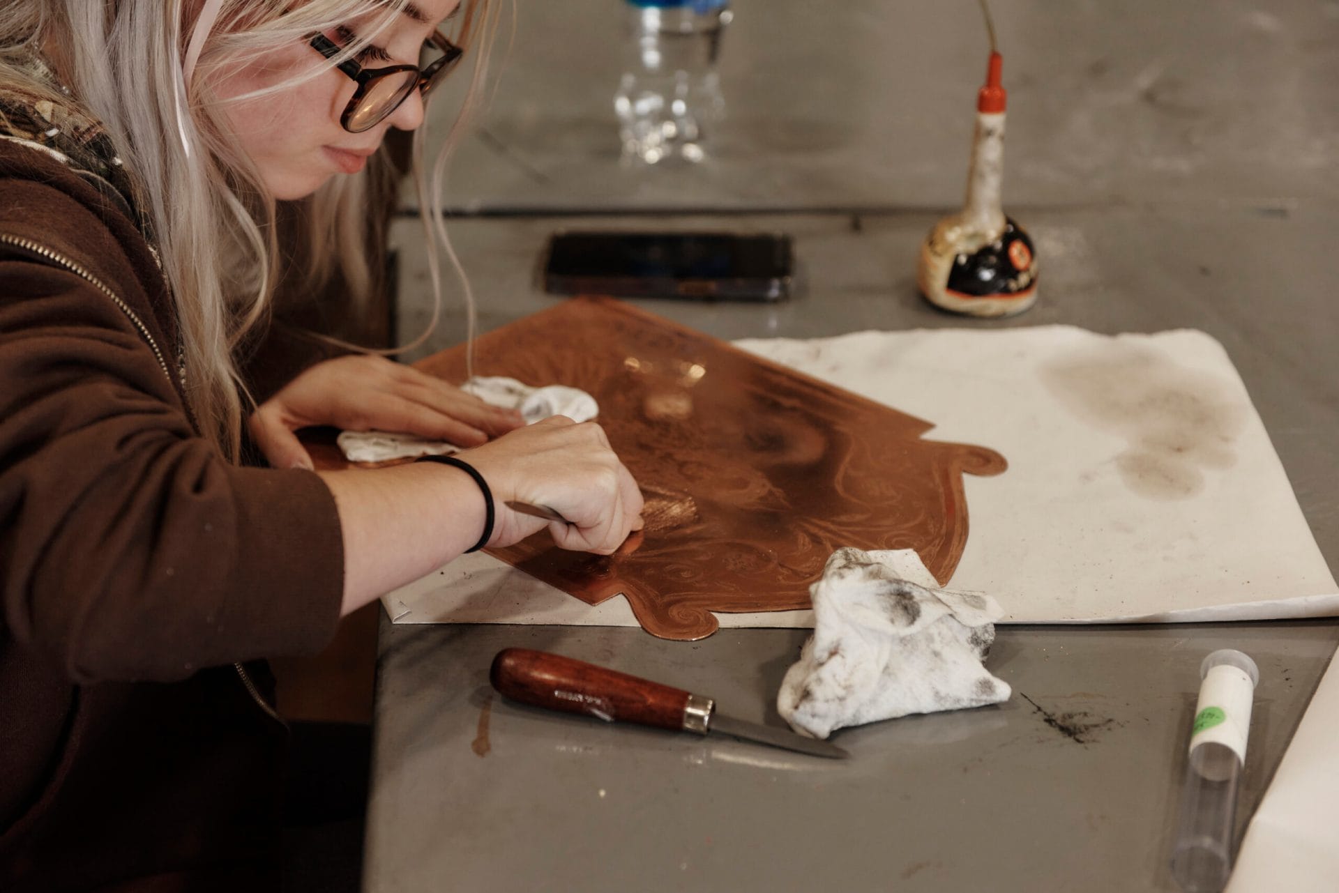 A student draws on a metal plate