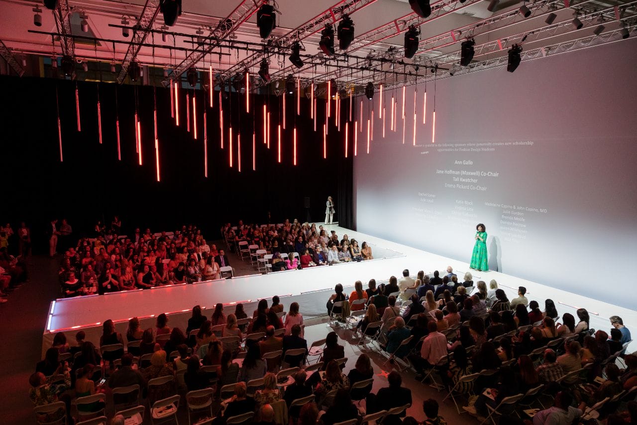 A white fashion runway is illuminated in a large room with pink lights