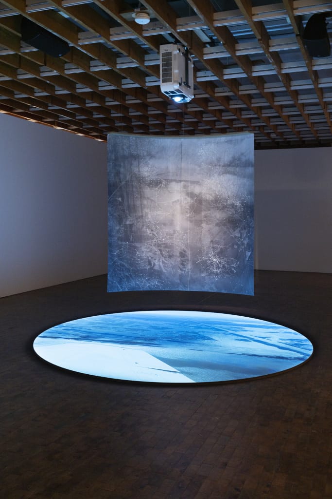 A projector shines on a hanging backdrop while a circle disk of light illuminates the floor