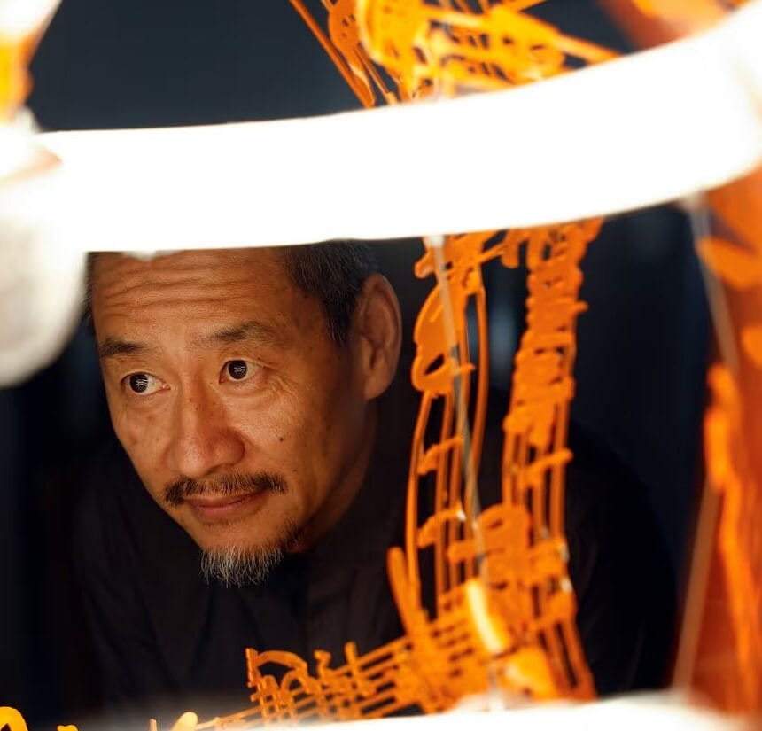 A photo of faculty member Fred Liang looking through one of his artworks.