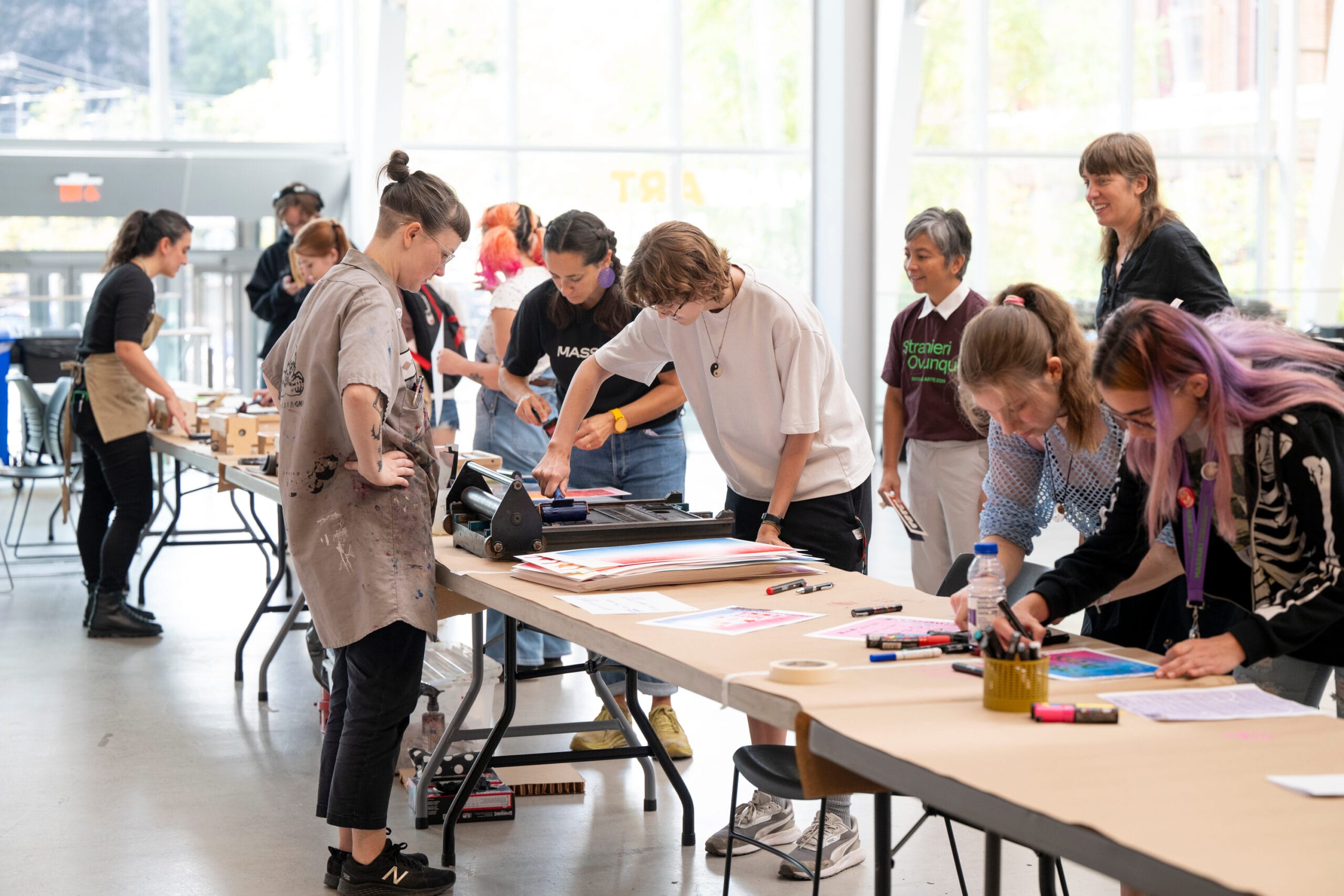 Students lean over long tables to make prints to encourage people to vote.