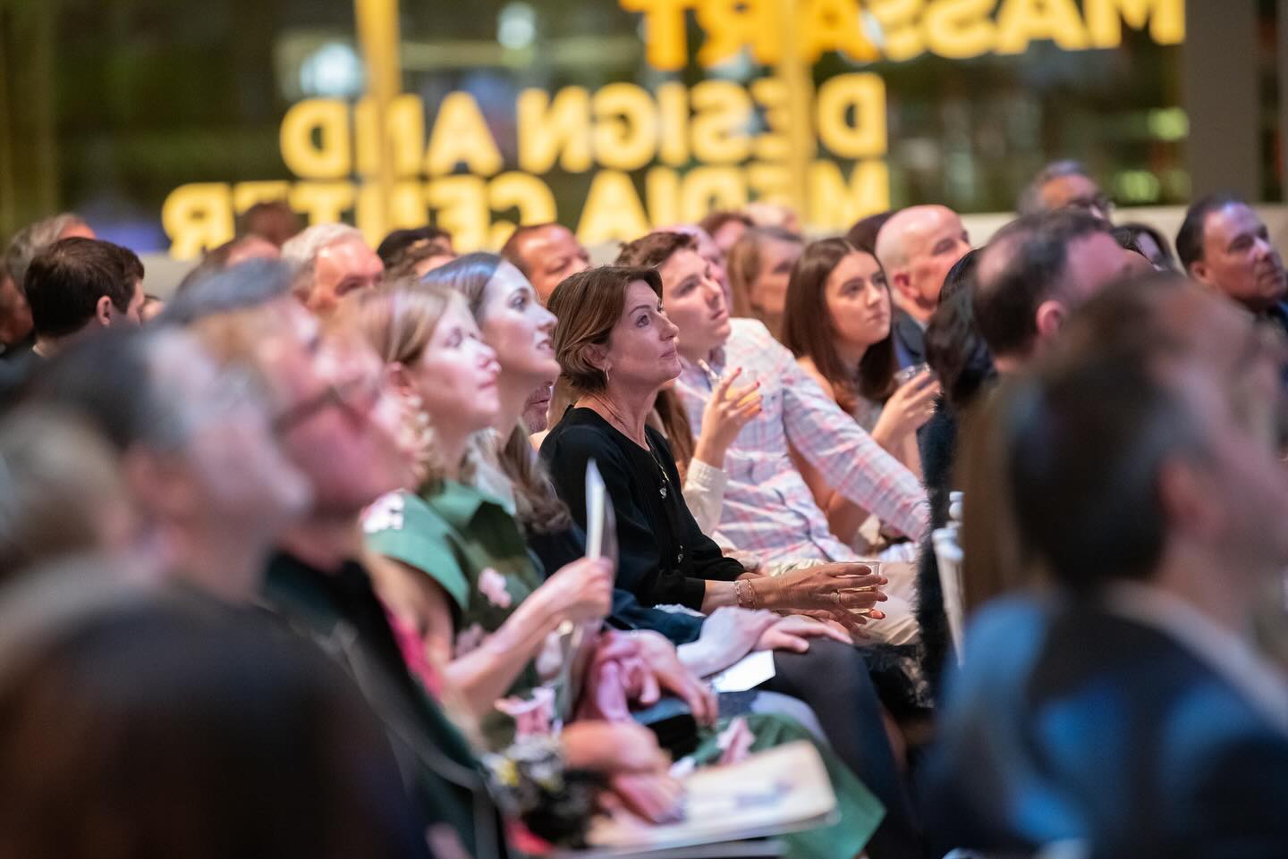 A crowd of people watch the live auctioneer at the MassArt Auction.
