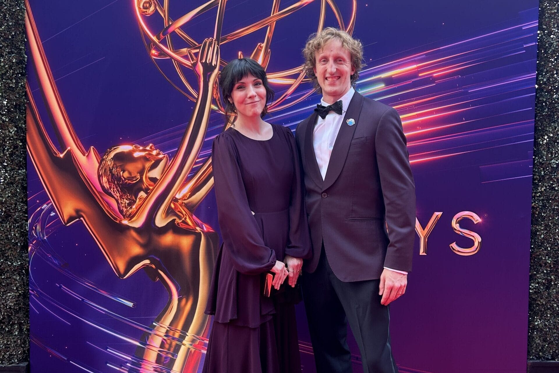 Lindsay and Alex Small-Butera dressed in formal clothing on the red carpet at the 2024 Emmy Awards.