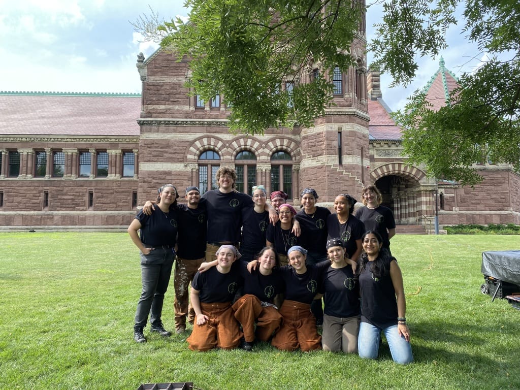 Students gathered on the lawn in front of a large brick building.