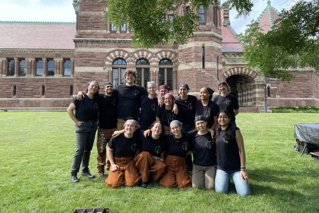 Students gathered on the lawn in front of a large brick building.