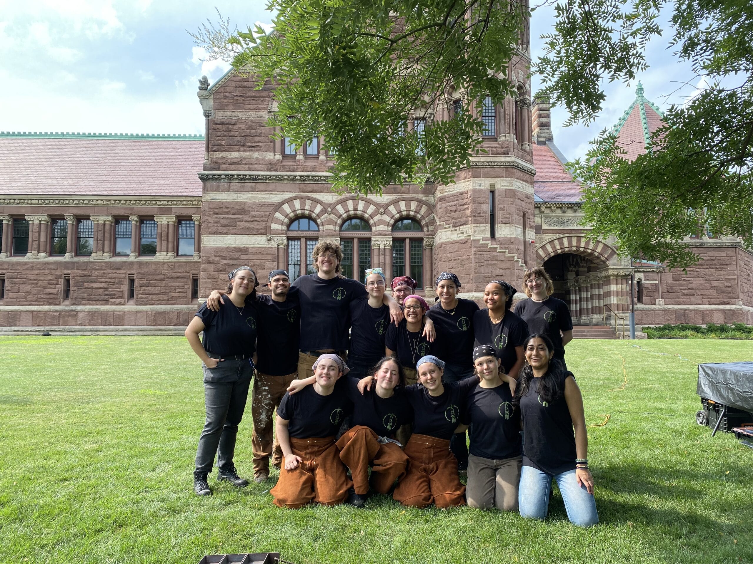 Students gathered on the lawn in front of a large brick building.