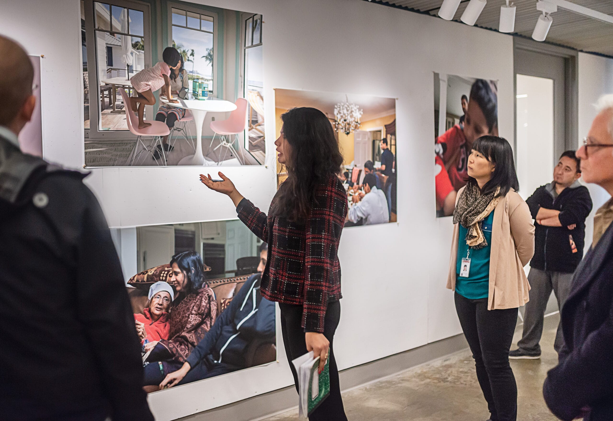 Graduate students standing in front of a wall of large, brightly lit, colorful photographs.