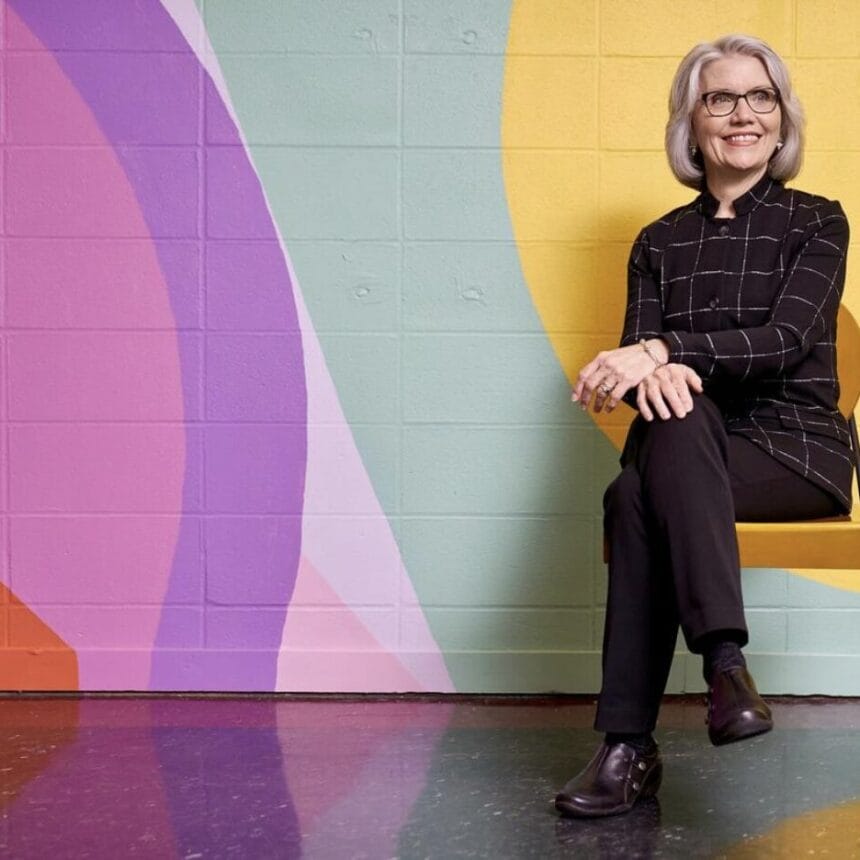 President Mary Grant sitting on a bench in front of a colorful wall.