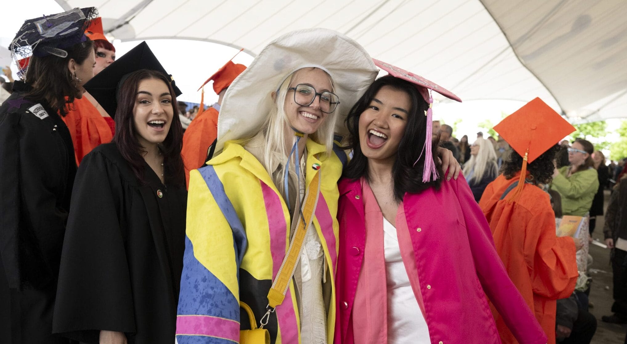 Colorfully dressed MassArt graduates smile for the camera.