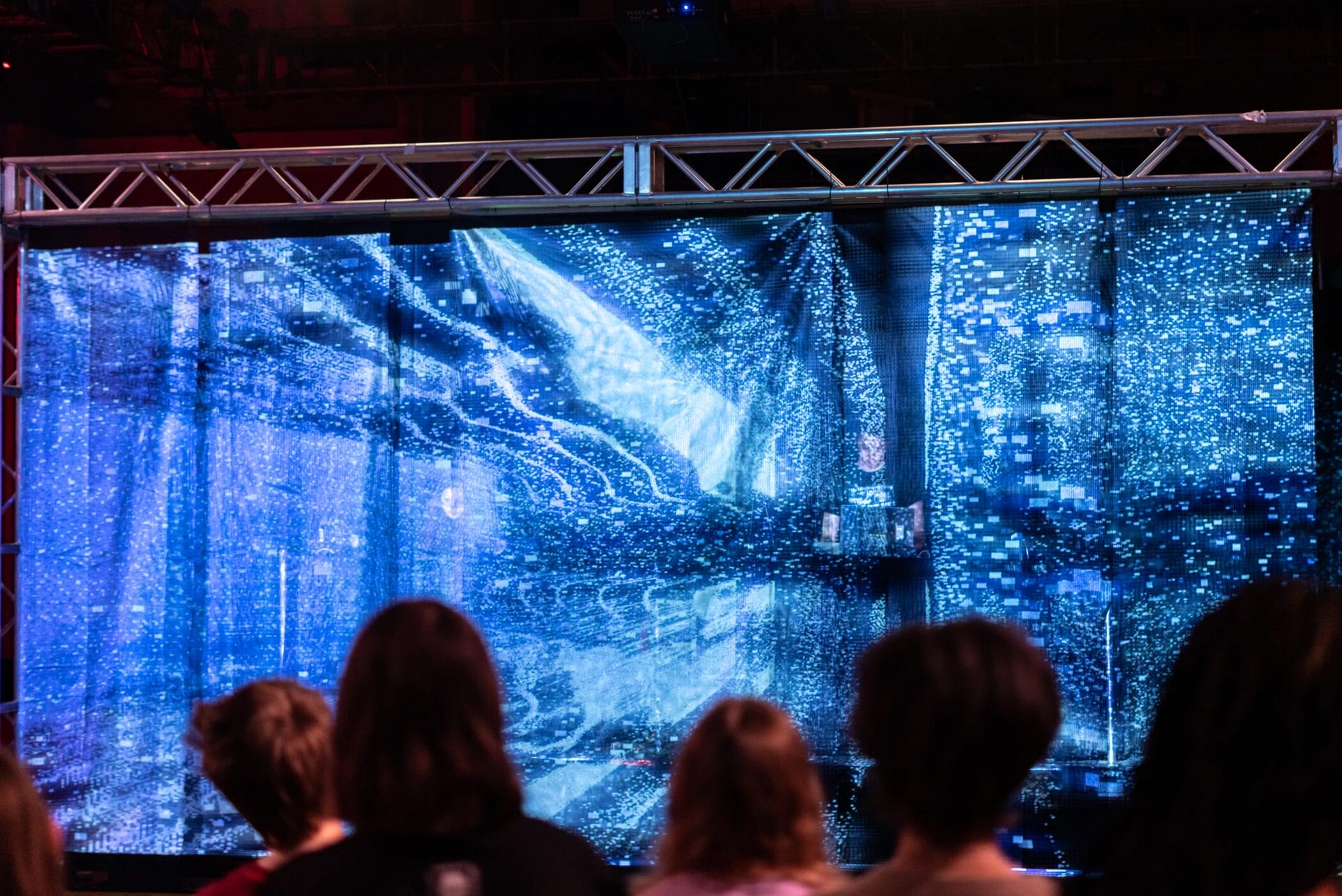 A blue video and sound projection performance in front of a live audience.