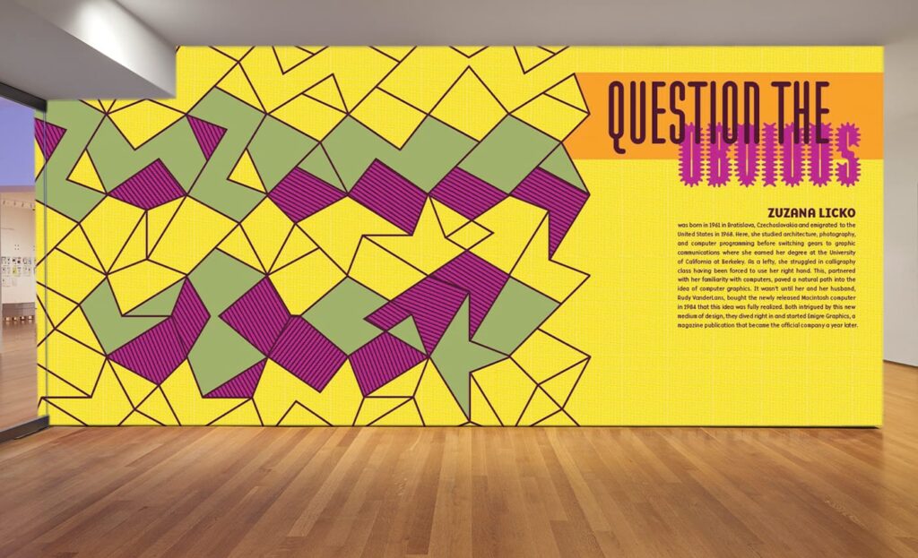 A vibrant geometric art display exhibits interlocking yellow, purple, and green shapes on a wall. The text reads QUESTION THE in bold lettering beside a paragraph detailing Zuzana Licko. The wooden floor adds contrast to the colorful design.