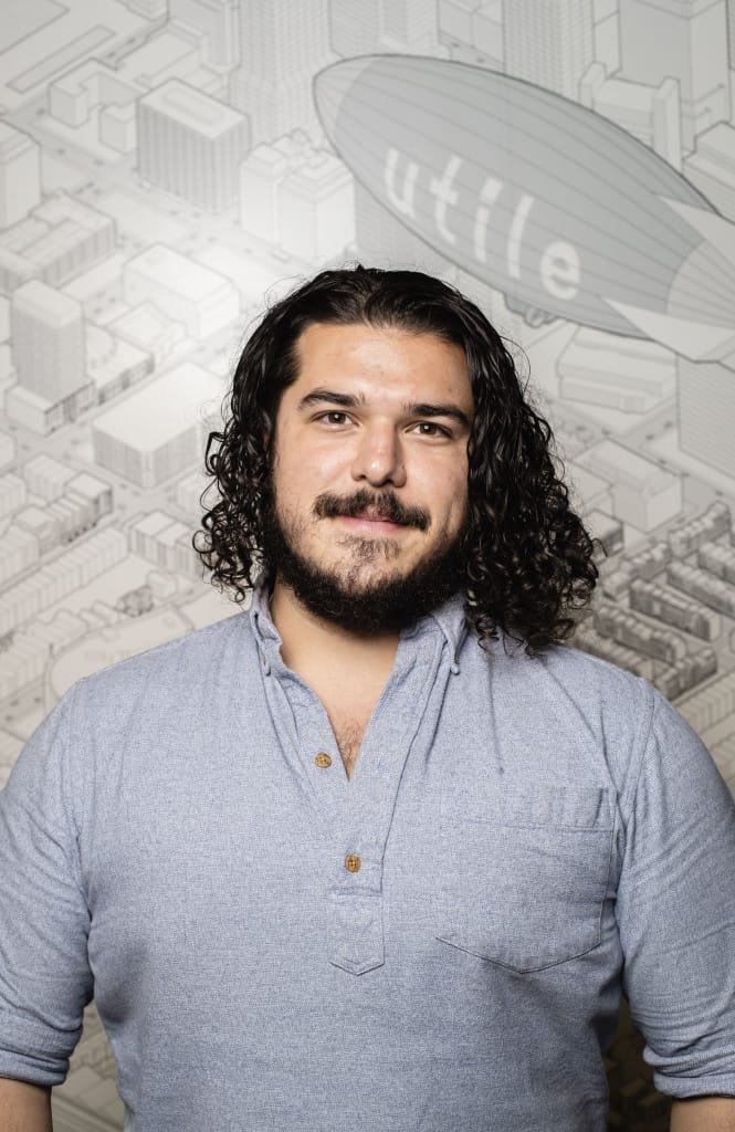 A photo of a man smiling with curly black hair and a beard - Cyrus Dahmubed.