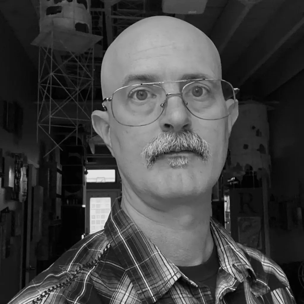 A bald man with a mustache and glasses