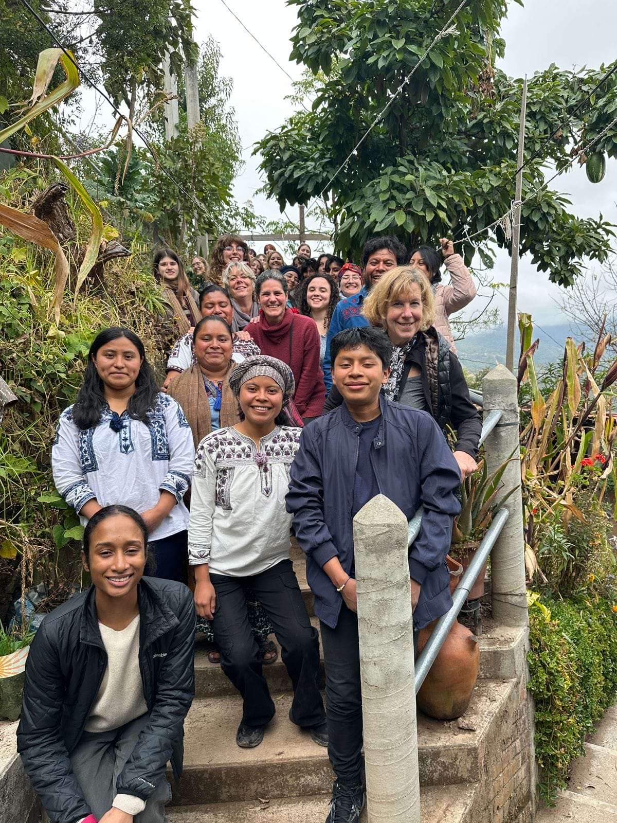 A group of students and faculty stand smiling on a staircase in a tropical locale.