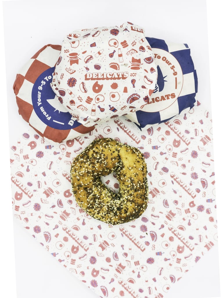 An everything bagel on a red and white printed wrapper