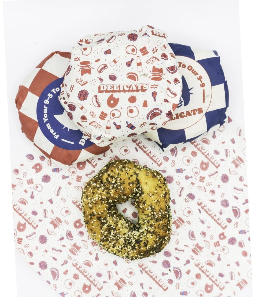An everything bagel on a red and white printed wrapper