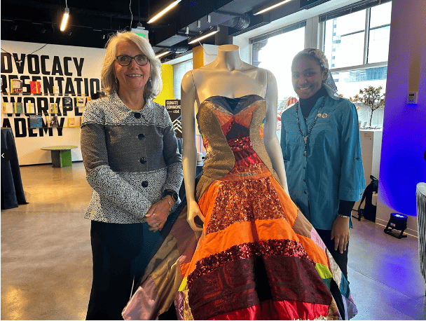MassArt president Mary Grant stands next to a dress form showcasing the work of a MassArt Alumna and her fashion design.